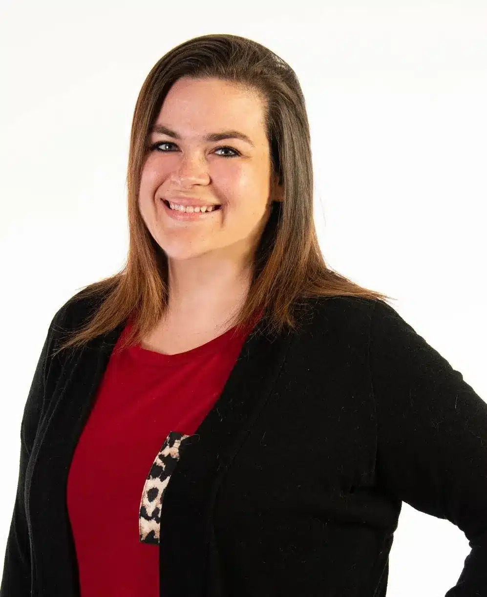 Smiling woman in a black cardigan over a red top with a leopard-print pocket, standing against a plain white background, embodying the confidence gained through pulmonary rehab.