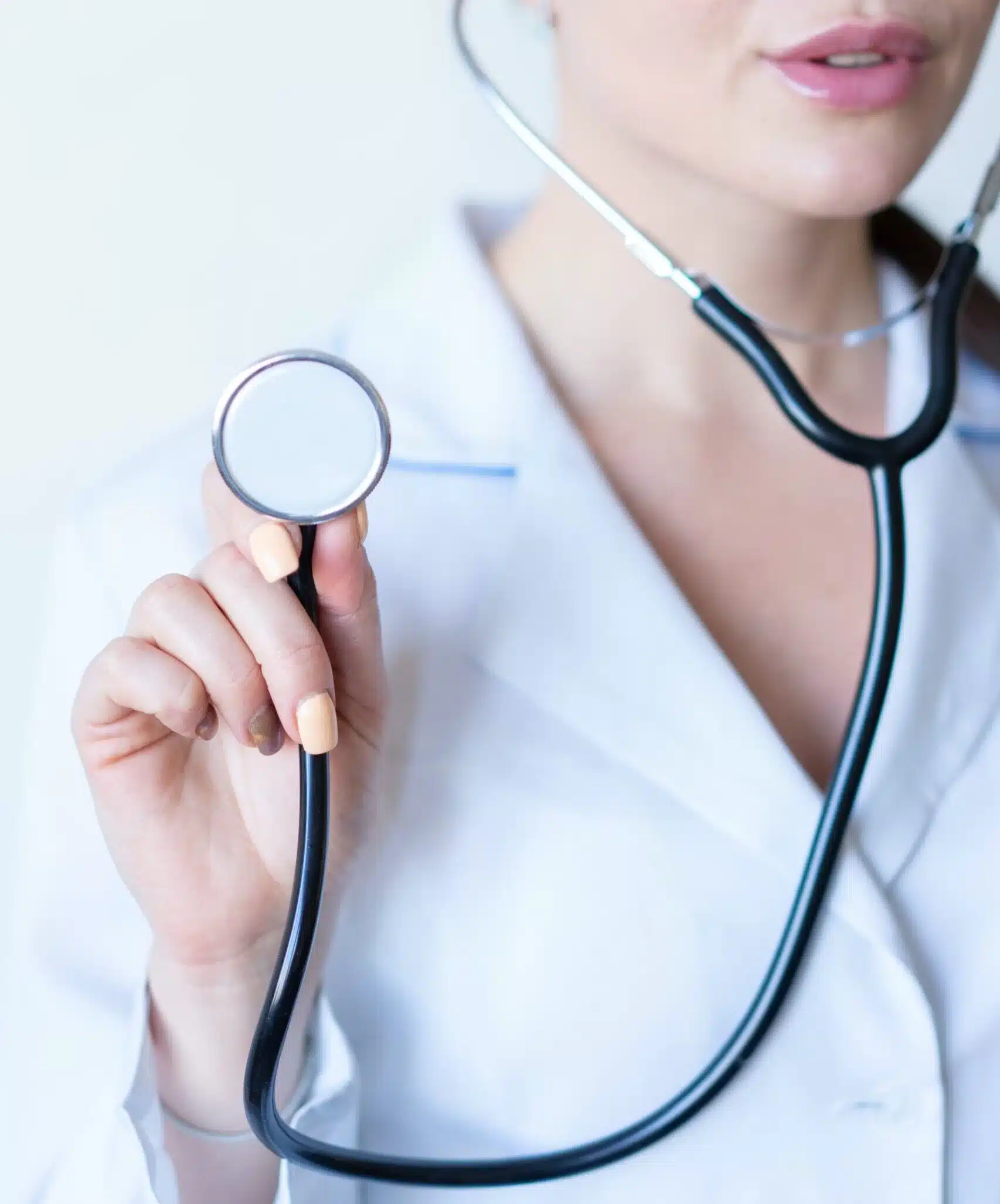 A healthcare professional in a white coat, specializing in pulmonary rehab, holds a stethoscope. The focus is on the stethoscope and the expert's steady hand, set against a blurred white background.