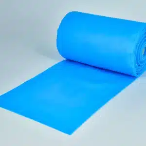 A roll of PT/OT Non-Latex Therapy Bands in bright blue is partially unrolled on a plain white surface, appearing smooth and reflective, with the roll standing upright on one end.